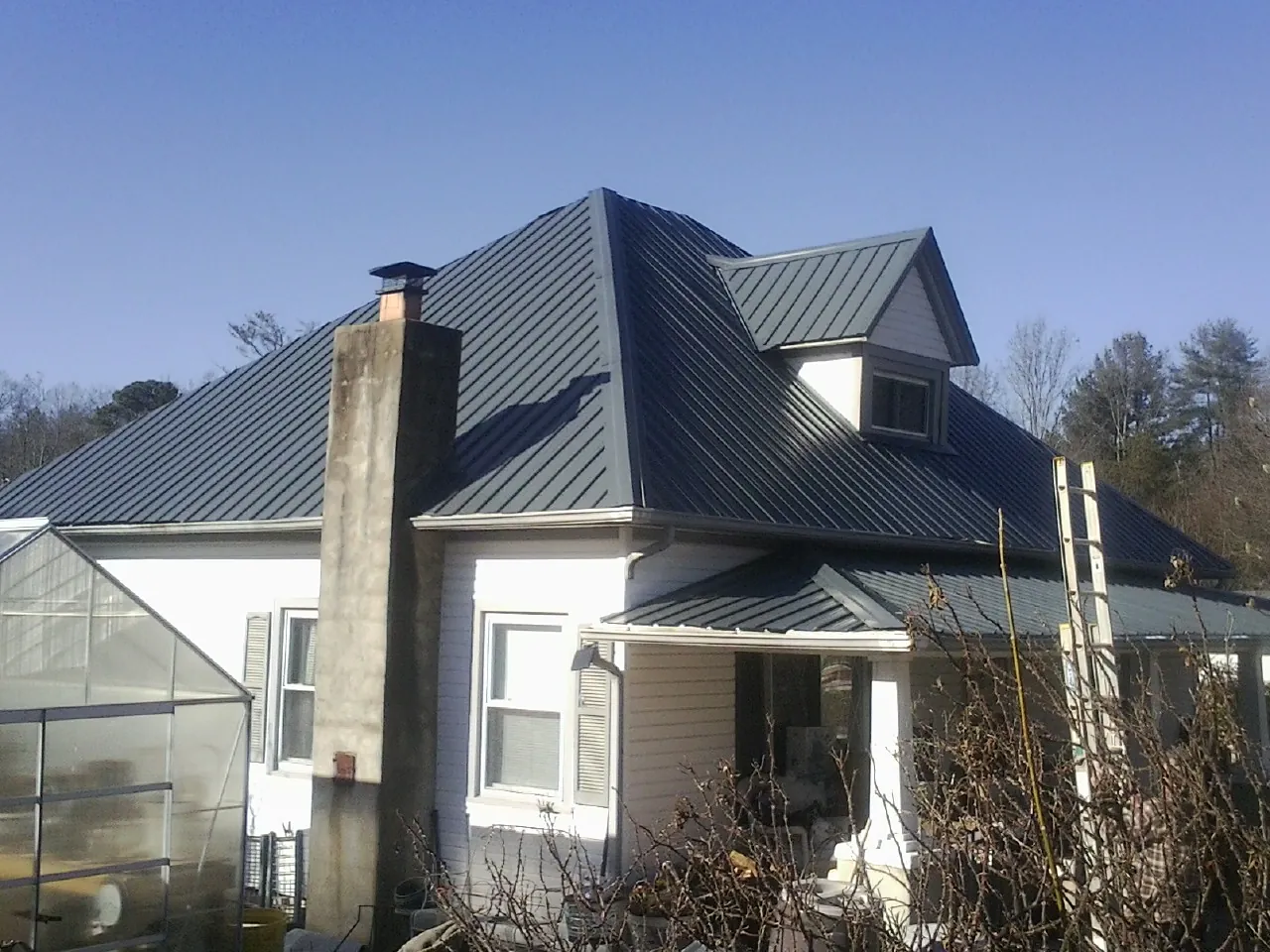 Dark blue standing seam metal roof on a white farmhouse with dormer — Slate & Tile Roof Repair by Roofing Brothers in South Bend