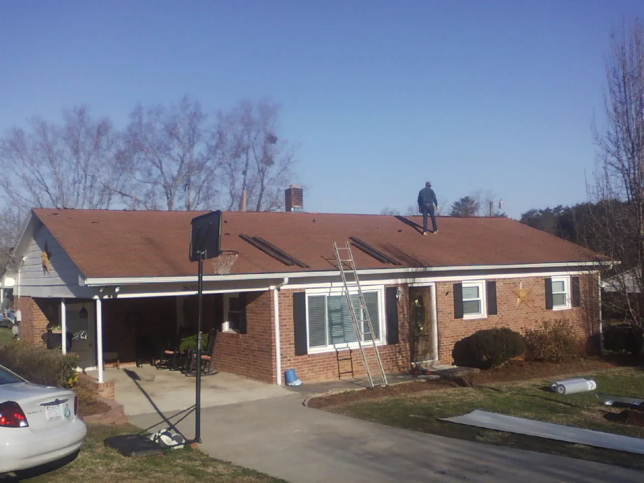 Roofer stripping a shingle roof on a brick ranch before metal panels in South Bend